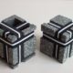 Two square stoneware cubes with nine elastics each.